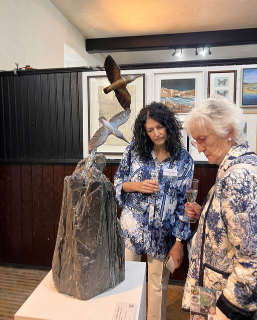 Visitors take a look at Kingfisher Waterfall by Sculptress JOEL at Lamport Hall central Exhibition checking the details