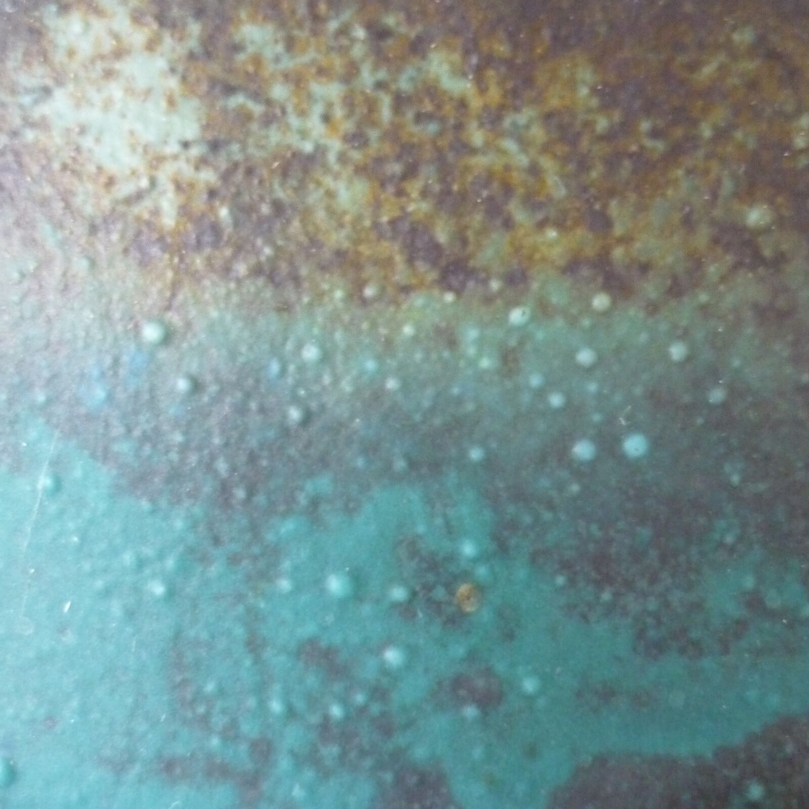 Close up surface of fired pot showing bubbles within the overlaid effect of the glazes